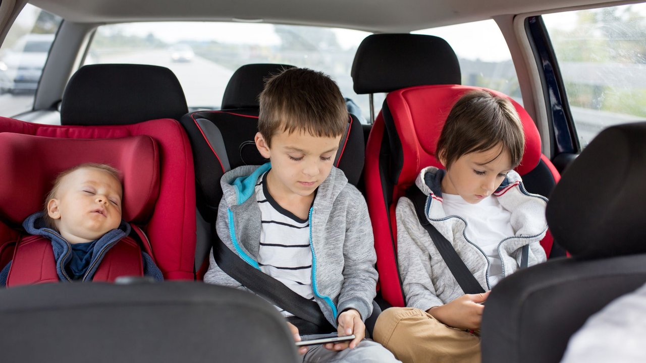 5 Gründe für ein Rauchverbot im Auto mit Kindern: 3 Kinder unterschiedlichen Alters sitzen auf der Rückbank