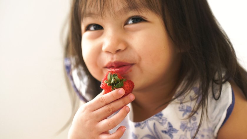 Kleines Mädchen nascht Erdbeeren
