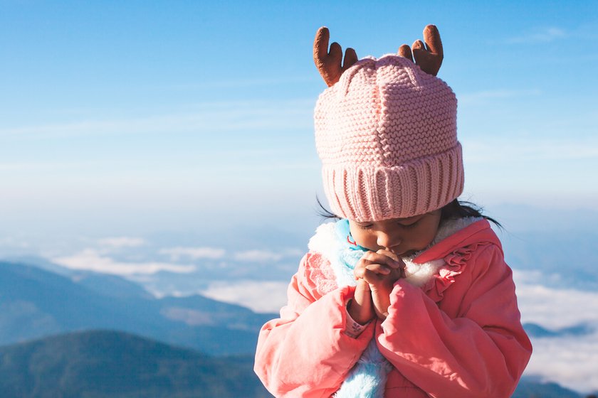 Mädchen betet auf Berggipfel