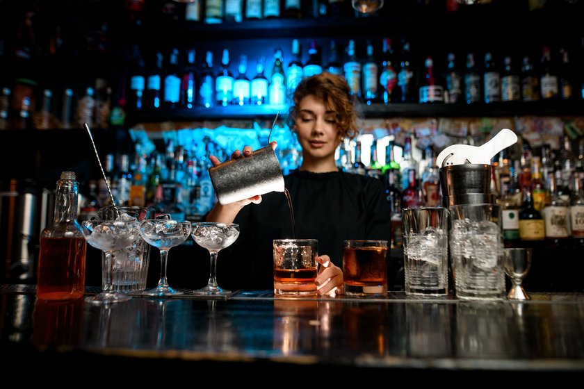 Junge Frau bereitet Cocktails an der Bar zu