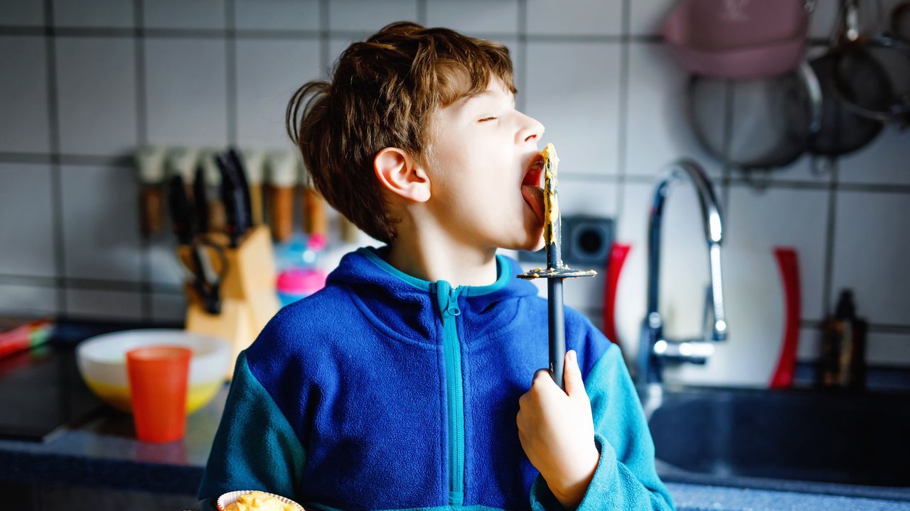 Deal Muffin-Transportbox: Junge mit Muffinblech in der Hand schleckt Teiglöffel ab