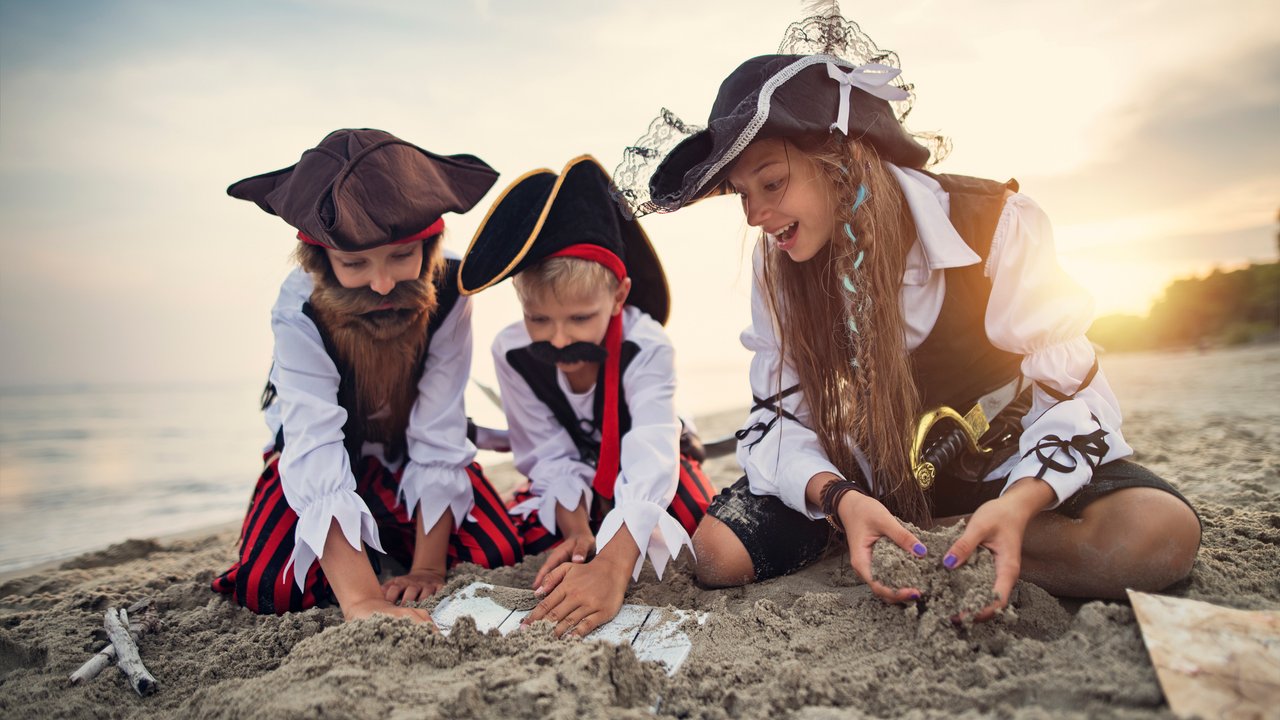 Three little pirates, a girl and two boys are playing pirates on the beach. They have found a treasure chest buried in the beach sand.
Sunny summer day.
Nikon D850
