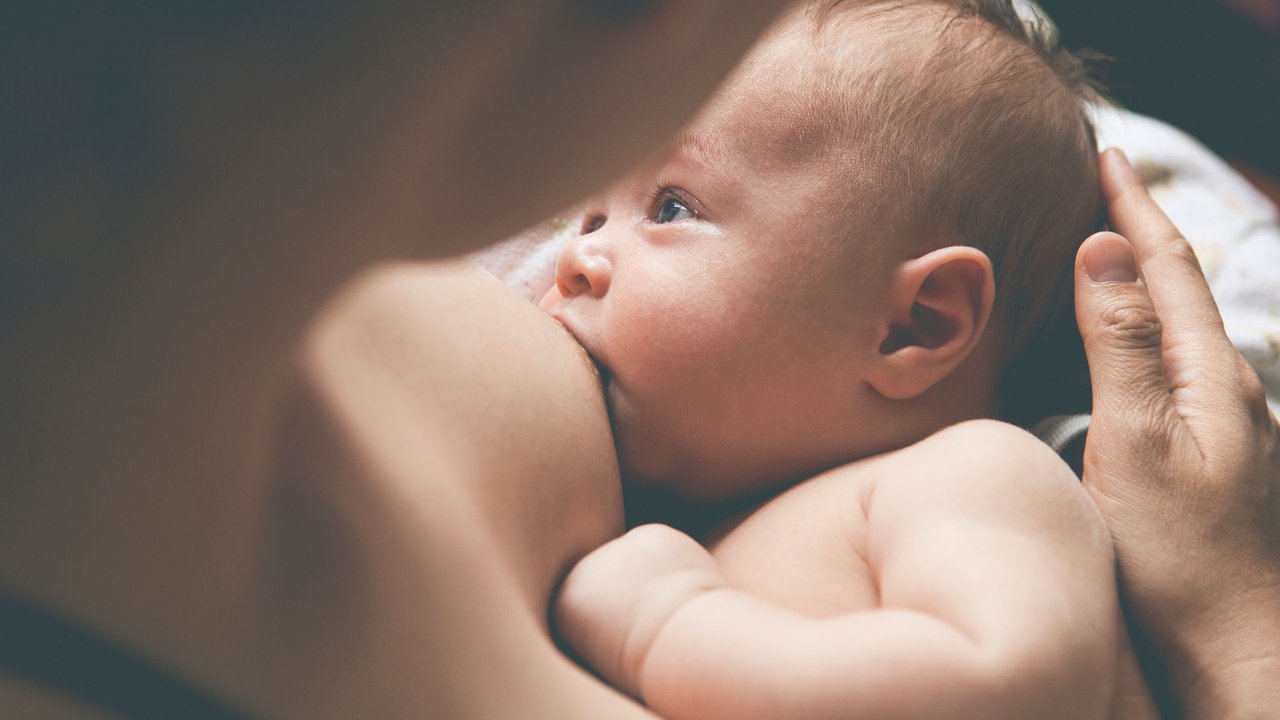 Schmerzen beim Stillen: Baby trinkt an der Brust seiner Mutter