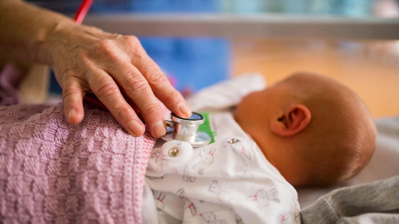 Wie lange kommt die Hebamme: Hebamme untersucht neugeborenes Baby