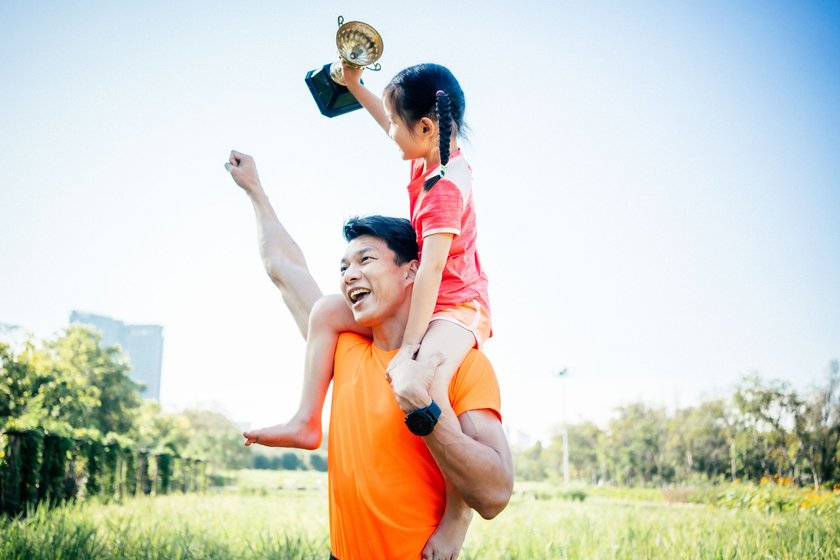 Vater und Tochter feiern mit einem Pokal in der Hand