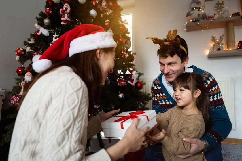 Parents and their daughter opening Christmas presents together.