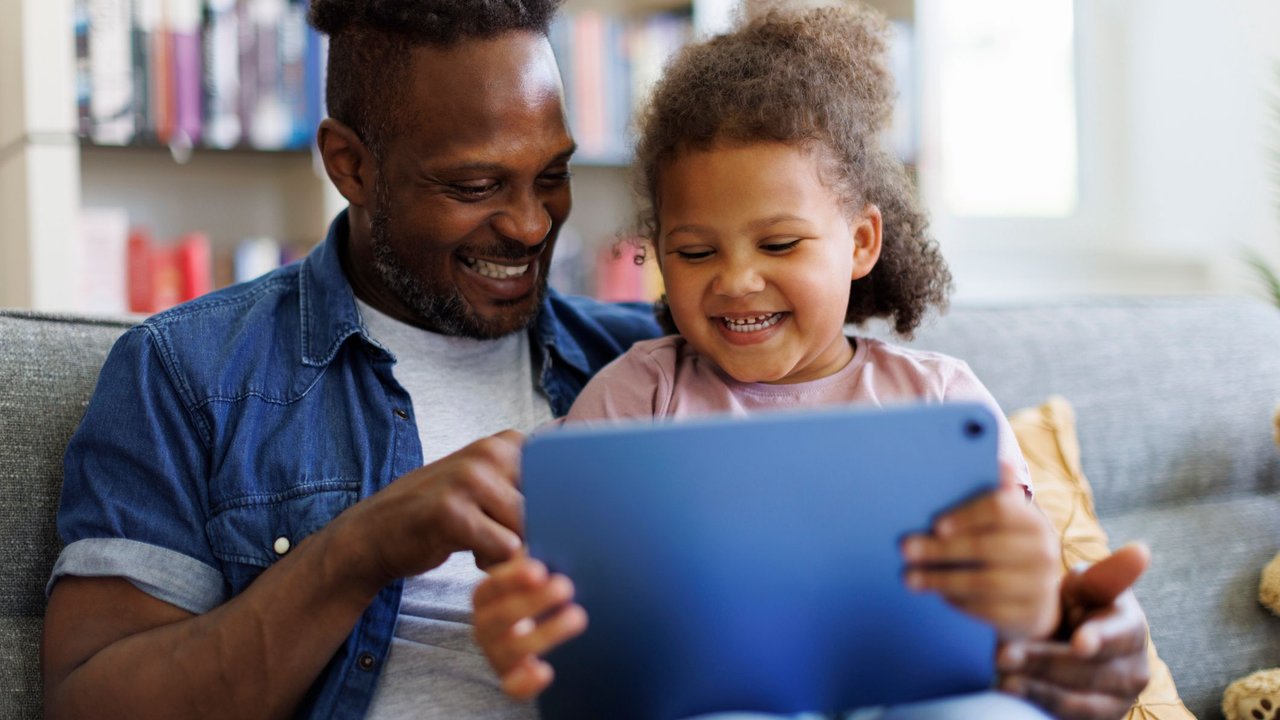 Father and daughter are having fun on a tablet at home