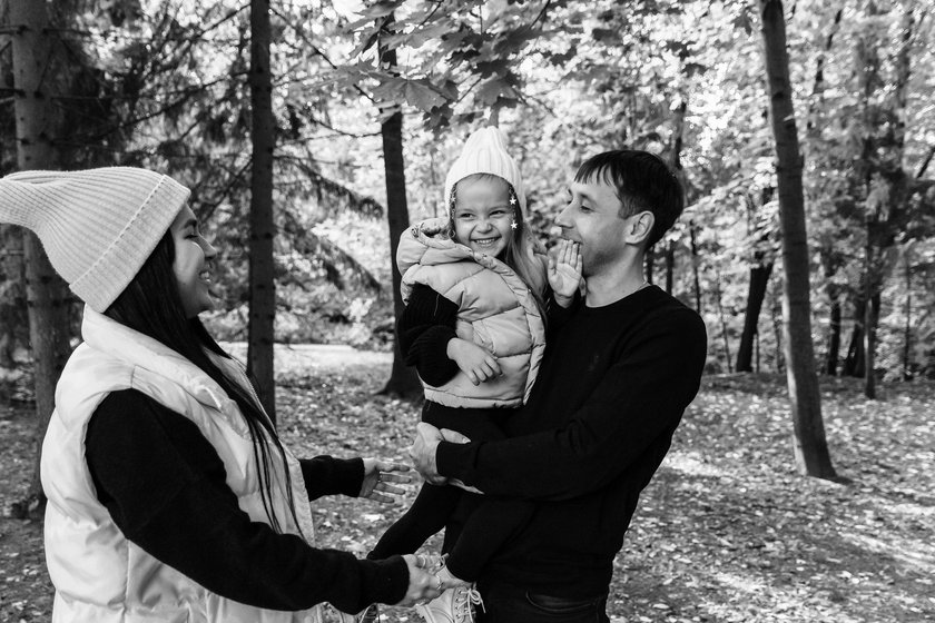 Woman and man and child in the park. Summer park. Green trees. The concept of a young family. Black and white photography