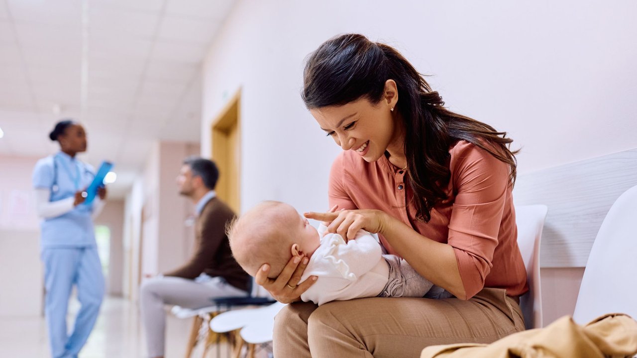 Nachsorgeuntersuchung nach der Geburt: Mama mit Neugeborenem im Wartezimmer