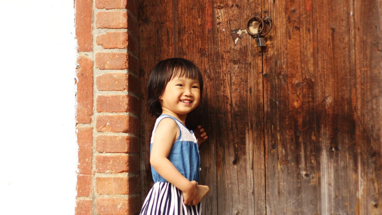Klopf Klopf Witze: Mädchen klopft an schwere Holztür und lacht dabei