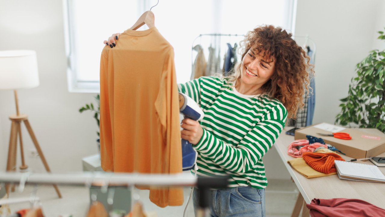 Frau glättet ihren Pullover mit einem Steamer