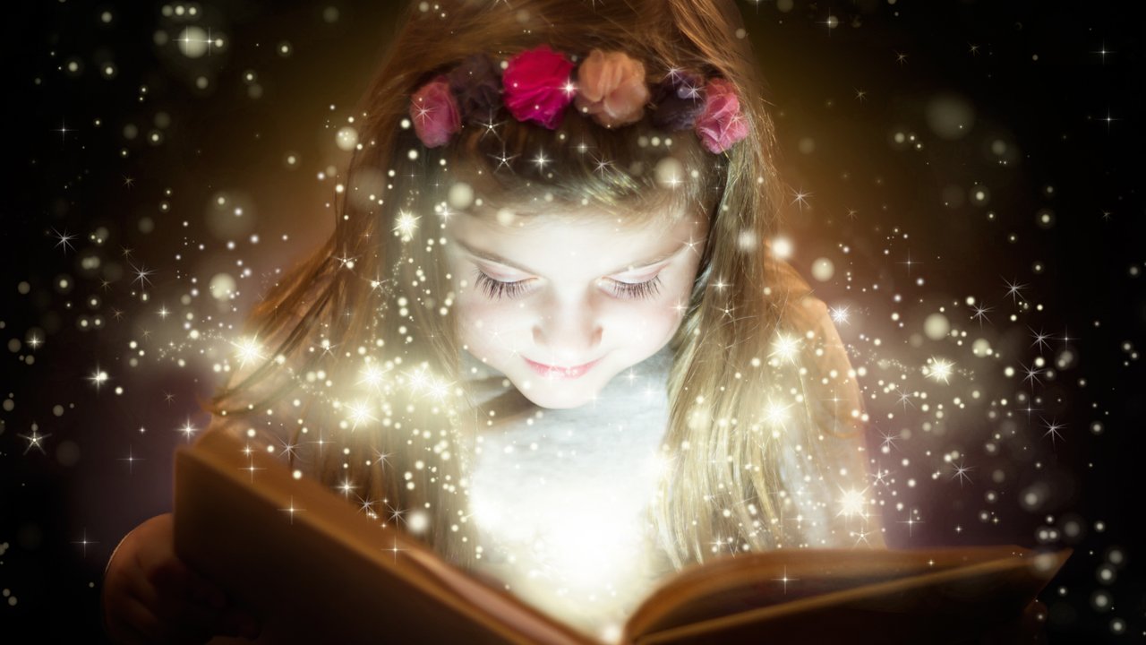 Beautiful little girl reading magic book