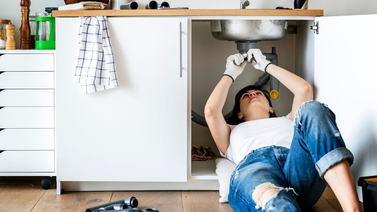 Woman fixing kitchen sink