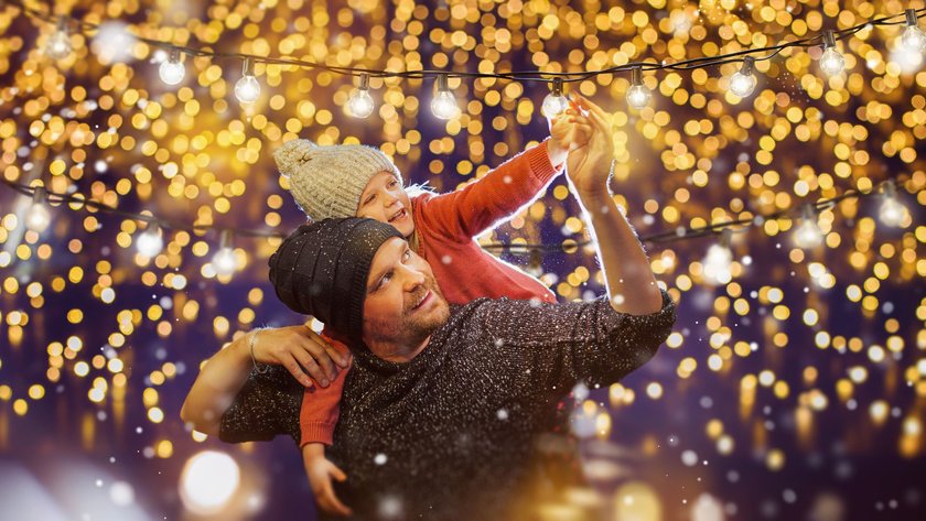 Vater und Tochter hängen gemeinsam Lichterketten auf