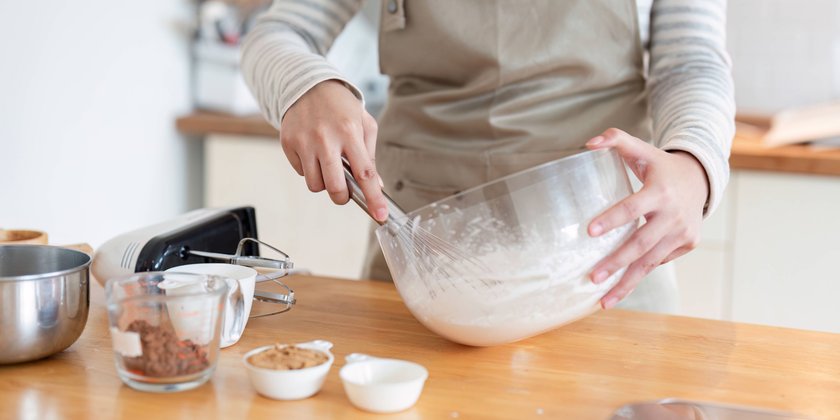 Close-up of mixing cake batter in modern kitchen setting Hands whisking cake batter in a clear bowl surrounded by various ingredients, portraying precision in a modern kitchen. ,model released, Symbolfoto Copyright: xZoonar.com/NATEExMEEPIANx 22136662 ,model released, Symbolfoto ,property released