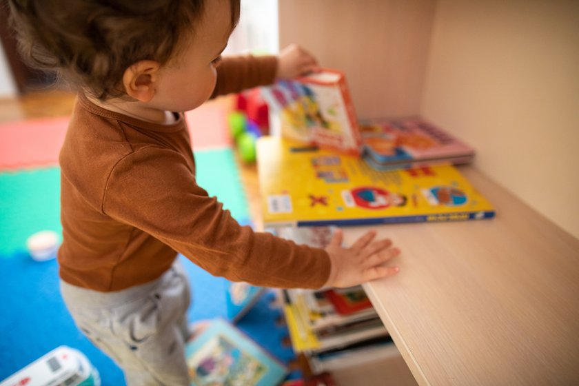 Aufräumen mit Kindern Fehler: Kleinkind am Bücherregal