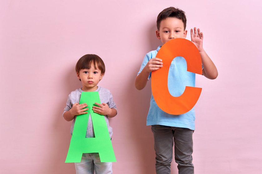 Studio portrait of kids with cutout letters on pink background