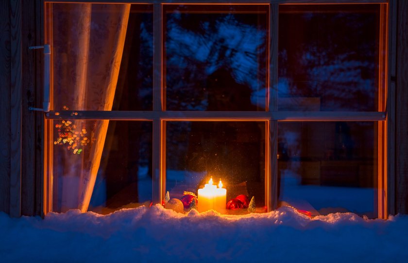 Kinder Weihnachtslieder: Holzfenster mit Schnee erleuchtet von Kerze bei Nacht 