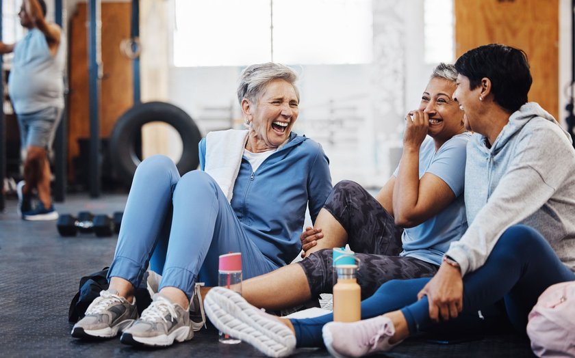 Herzhaft lachende Menschengruppe auf dem Boden eines Fitnessstudios