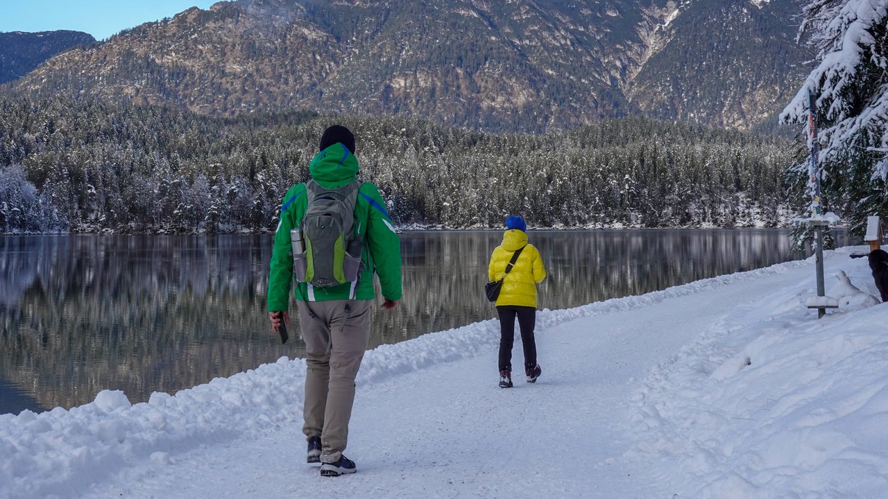 Schnee an einem See, Spazierweg, zwei Personen von hinten