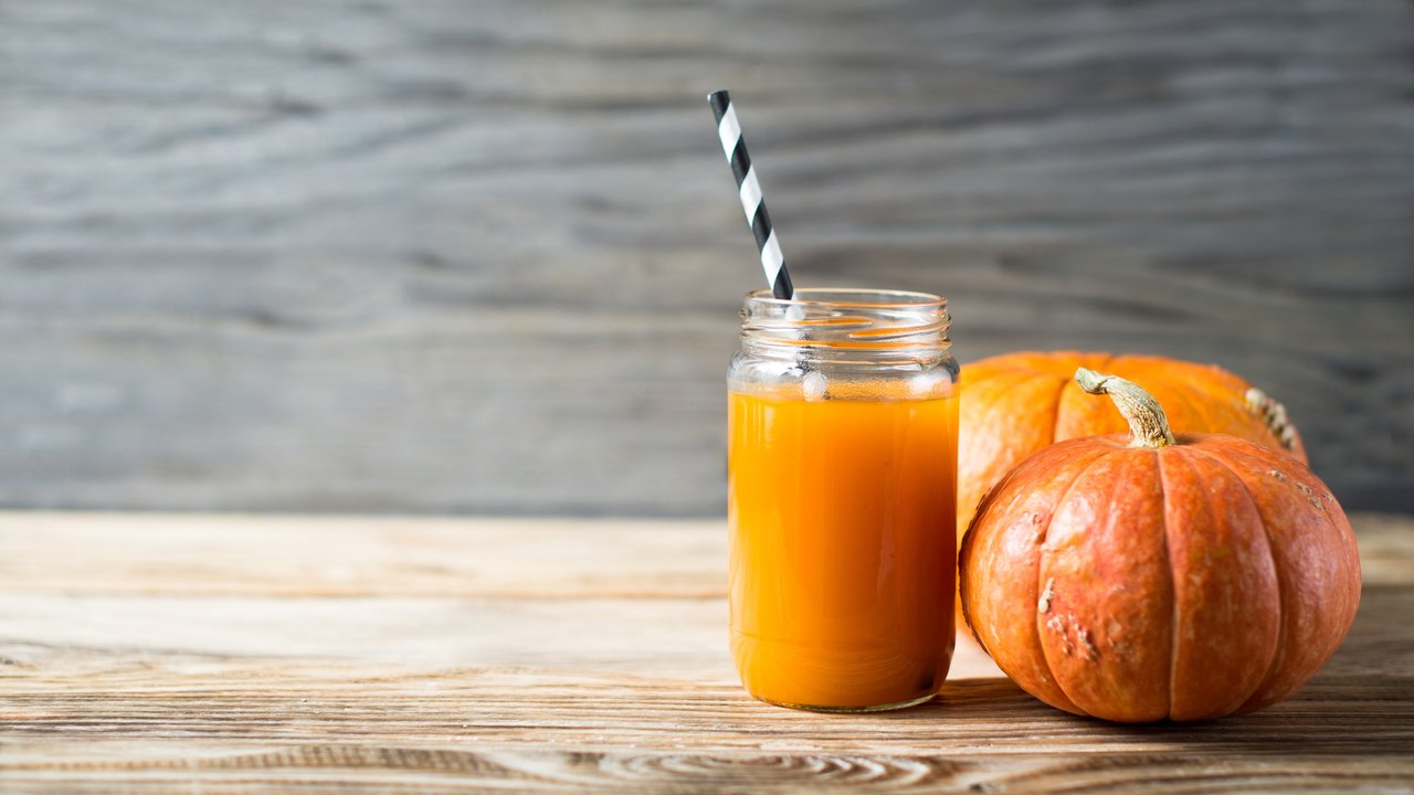 Pumpkins juice in bottle with pumpkins and cinnamon