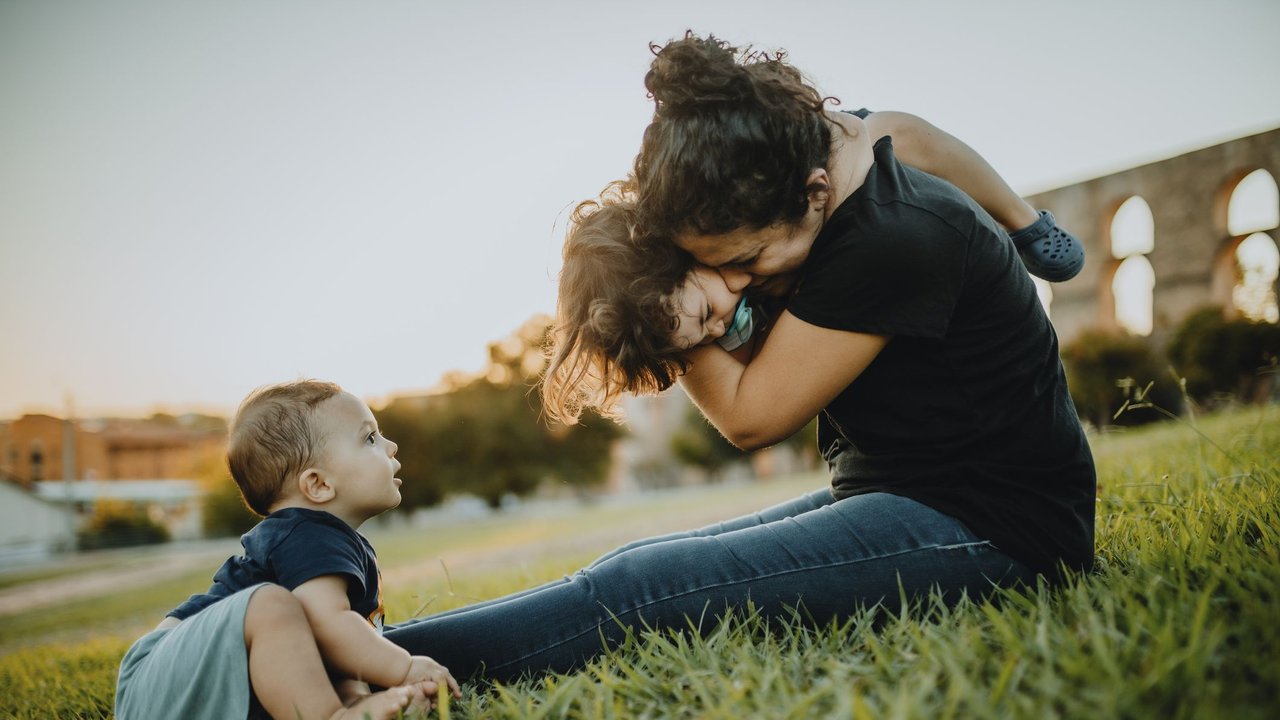 Kind fühlt sich benachteiligt: Mama spielt draußen mit Kindern 