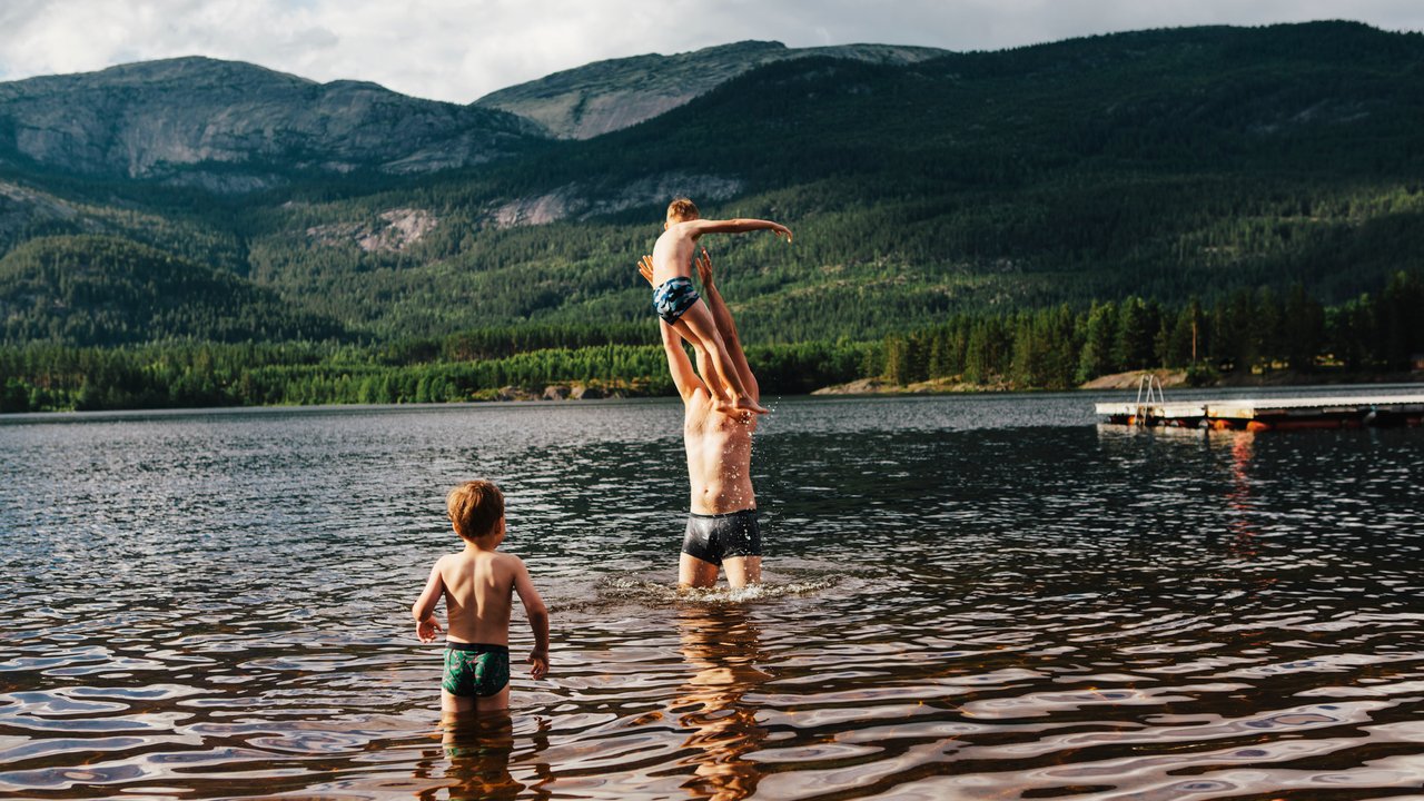 Baderegeln in Seen: Mann steht in Bergsee und wirft ein Kind in die Luft