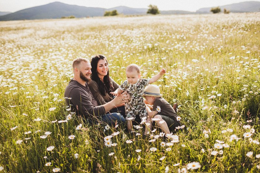 Summer mood. Family vacations trip, adventure journey with two children outdoors. Parents and sons having fun in field with flowers. Happy relations in family and togetherness. Laugh and smiles.