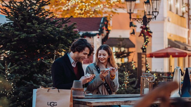 Ein Paar, das auf gemeinsam auf dem Weihnachtsmarkt isst.