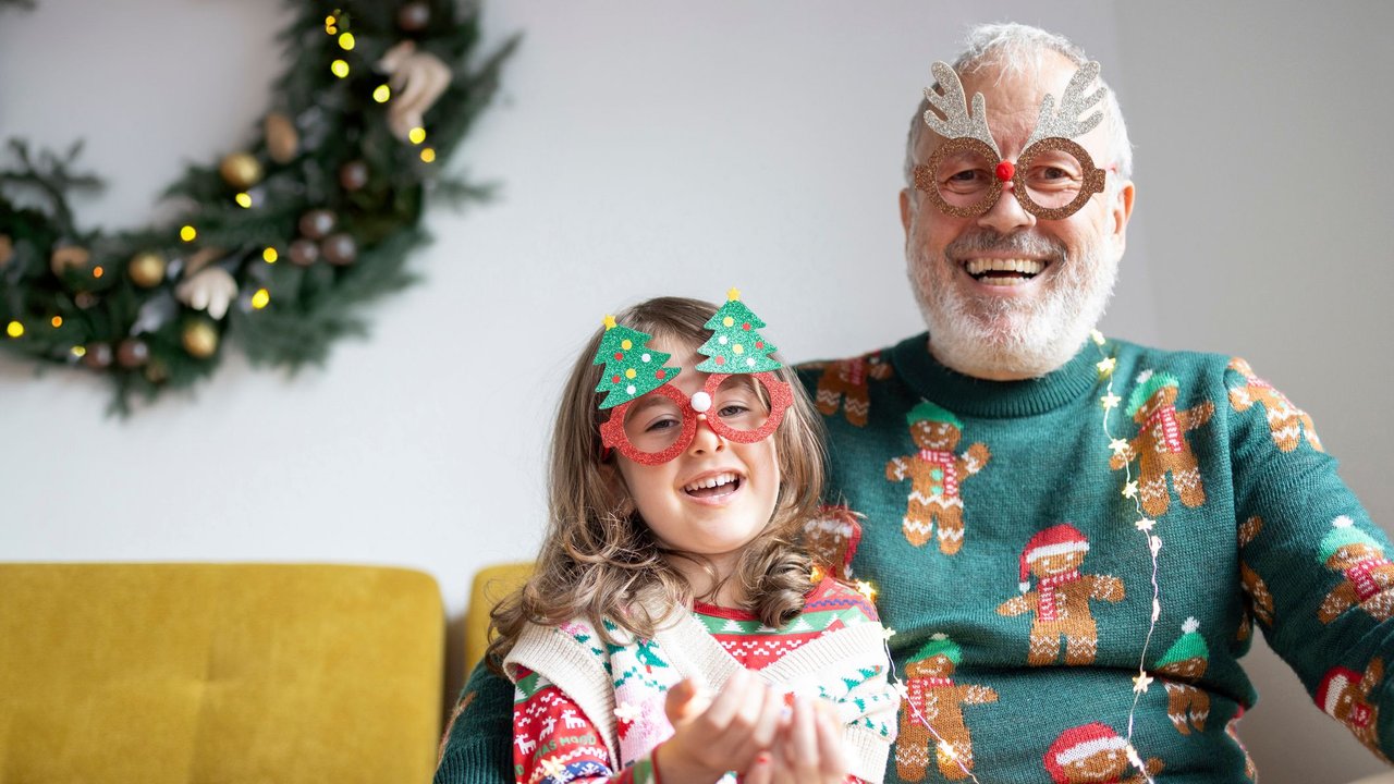 Lachender Großvater mit Enkelin im Weihnachtspulli