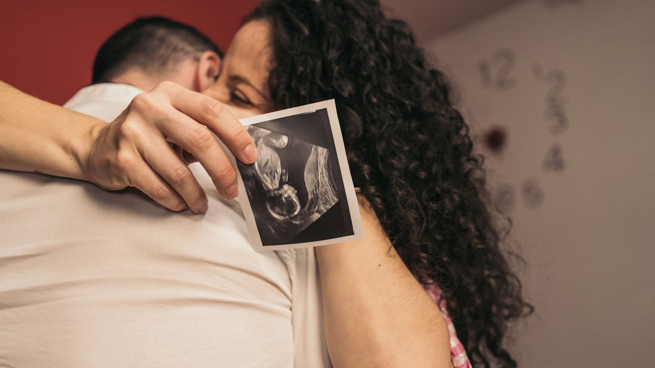 Untersuchungen in der Schwangerschaft: Paar umarmt sich mit Ultraschall-Bild 