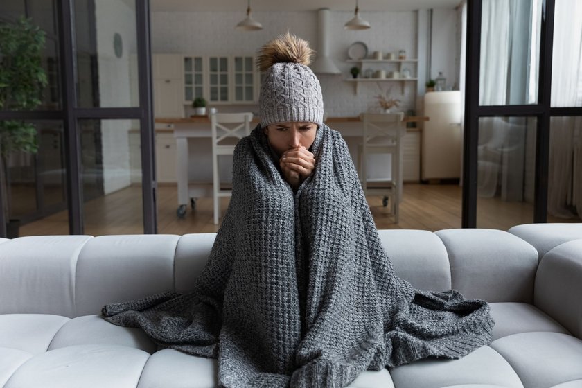 Frau sitzt zitternd auf einem Sofa