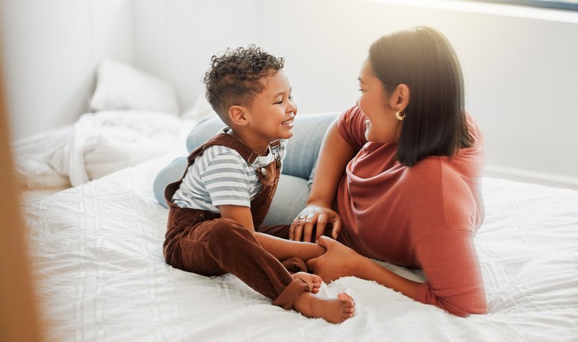 Glückliches Kind: Kind redet mit Mama im Bett
