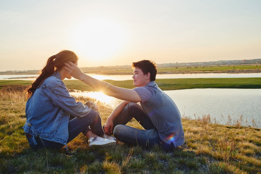 Junges Paar sitzt an einem Fluss im Sonnenuntergang