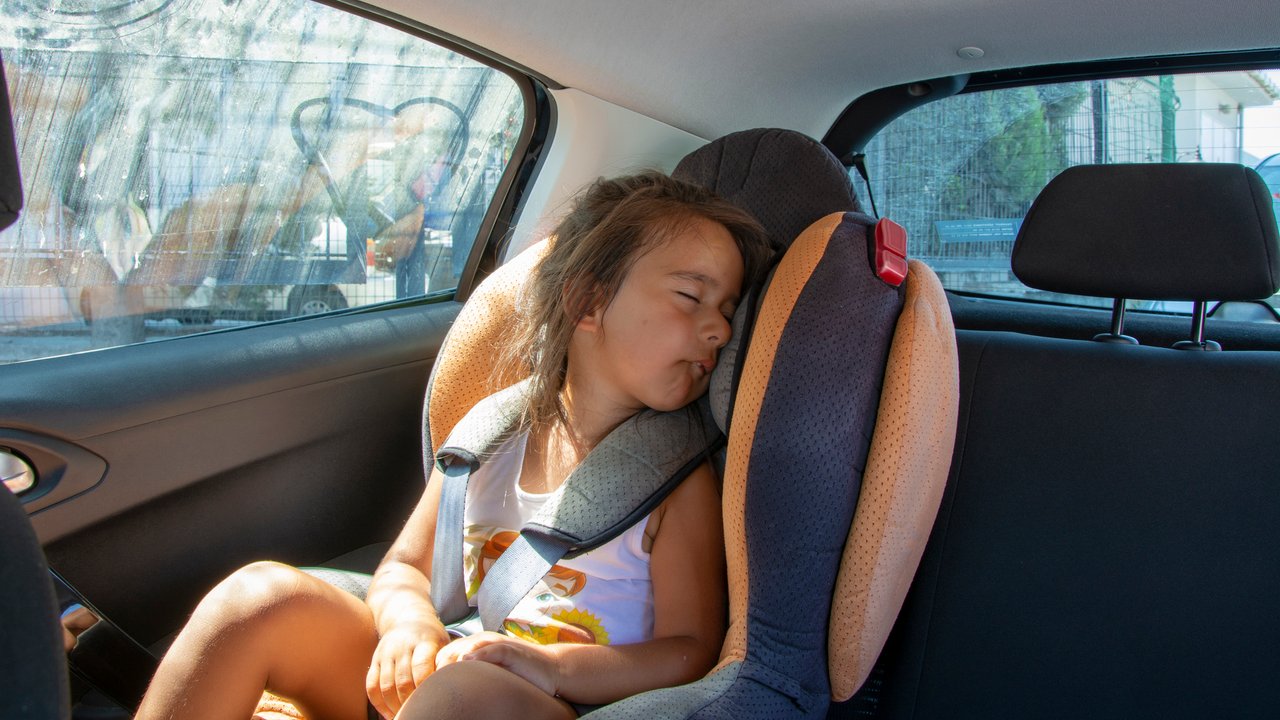 Kind hitze auto: Mädchen sitzt im Auto auf Kindersitz
