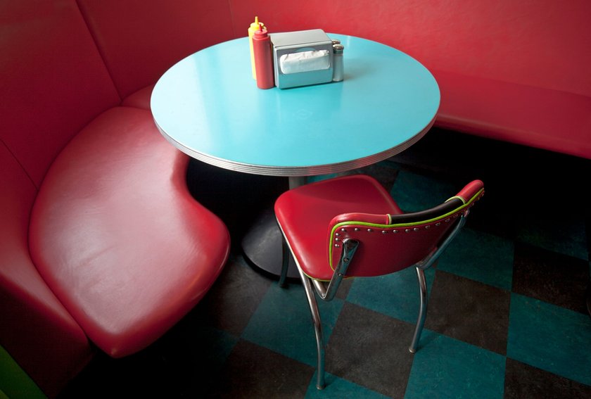 Retro red diner booth with chair, turquoise blue table, napkin holder, catsup, and mustard containers. Horizontal.