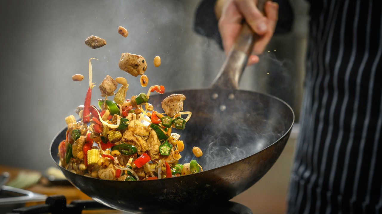 Koch bereitet Essen im Wok zu