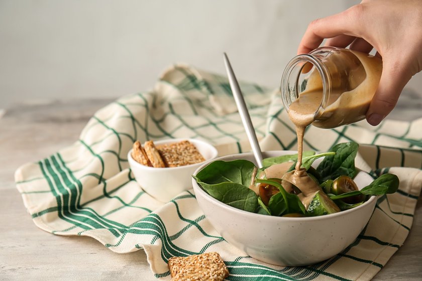 Eine Schüssel mit Salat wird mit frischem Tahini-Dressing angemacht