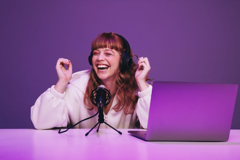 Lachende Frau nimmt einen Podcast im Studio auf