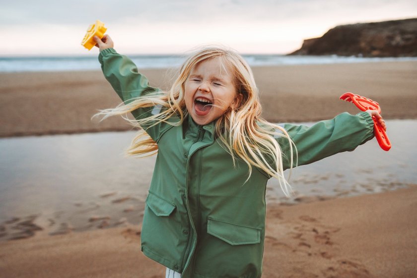 Glückliches Kind: Kind läuft lachend am Strand