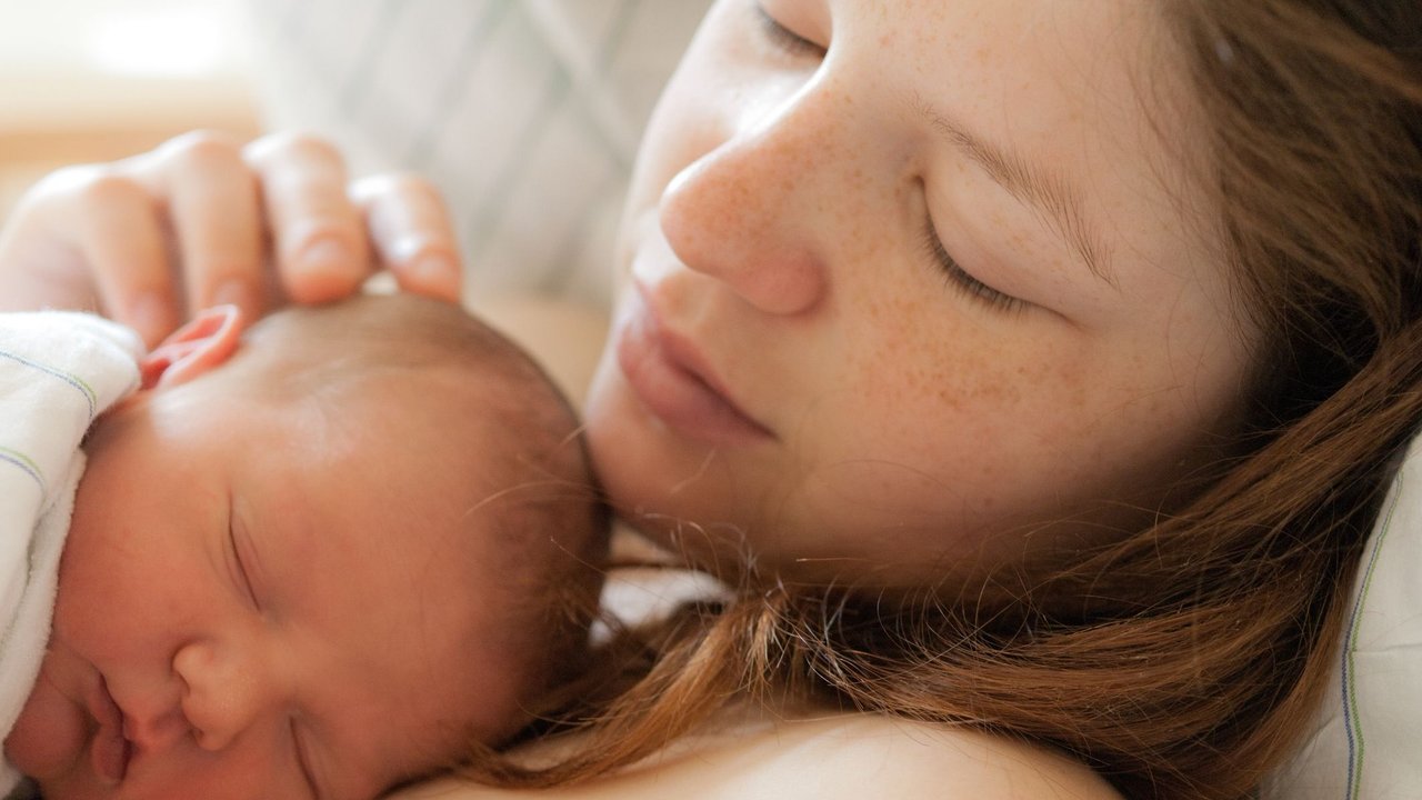 Labienriss: Frau liegt im Bett mit Neugeborenem auf dem Bauch