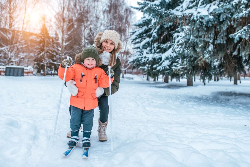 Werdende Mama mit Geschwisterkind auf Skiern im Schnee