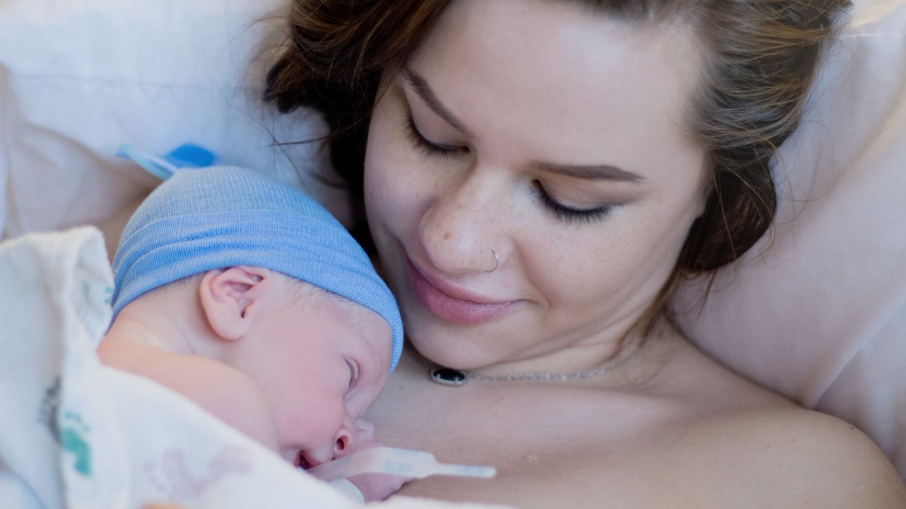 Neugeborenes Baby liegt in den Armen seiner Mutter