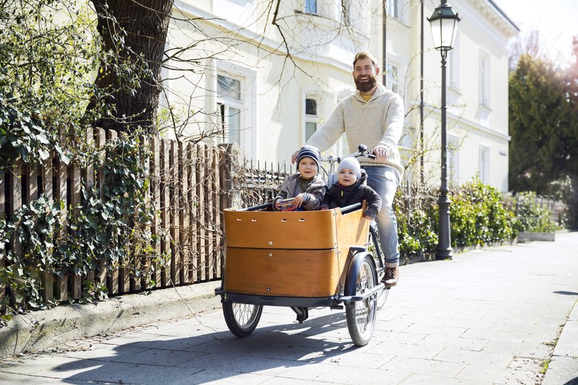 Happy father with two children riding cargo bike in the city model released Symbolfoto PUBLICATIONxINxGERxSUIxAUTxHUNxONLY MAEF12831