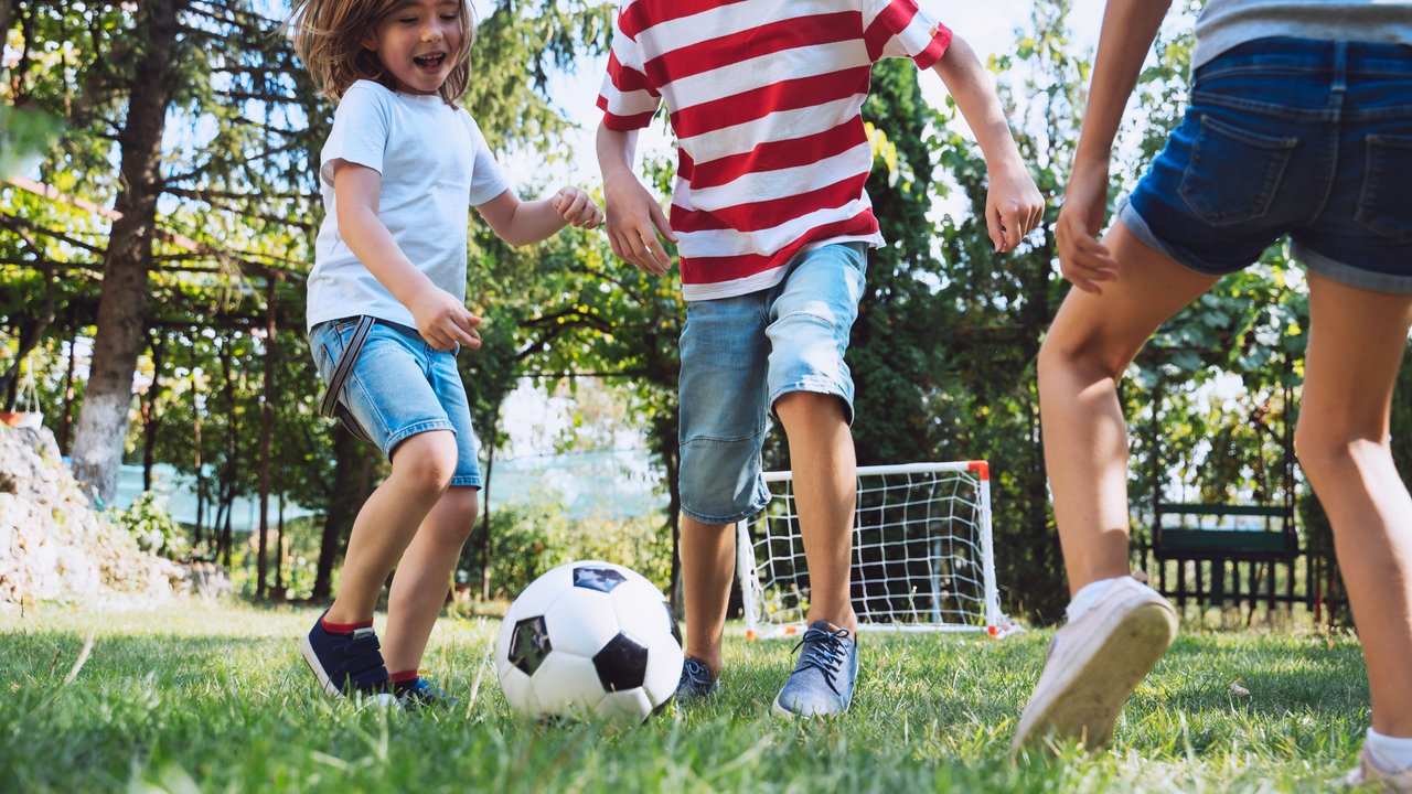 Kinder spielen Fußball und schießen auf ein Tor