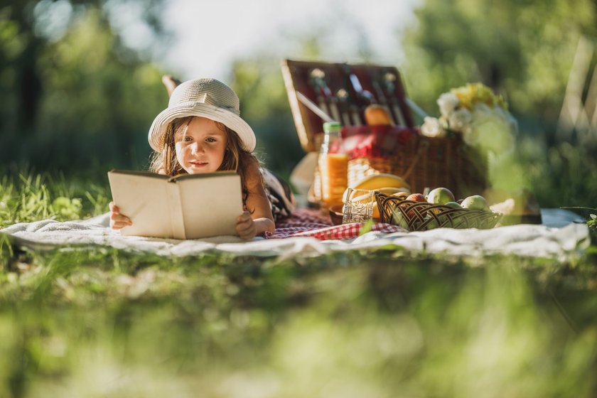 Mädchen liest ein Buch auf einer Wiese