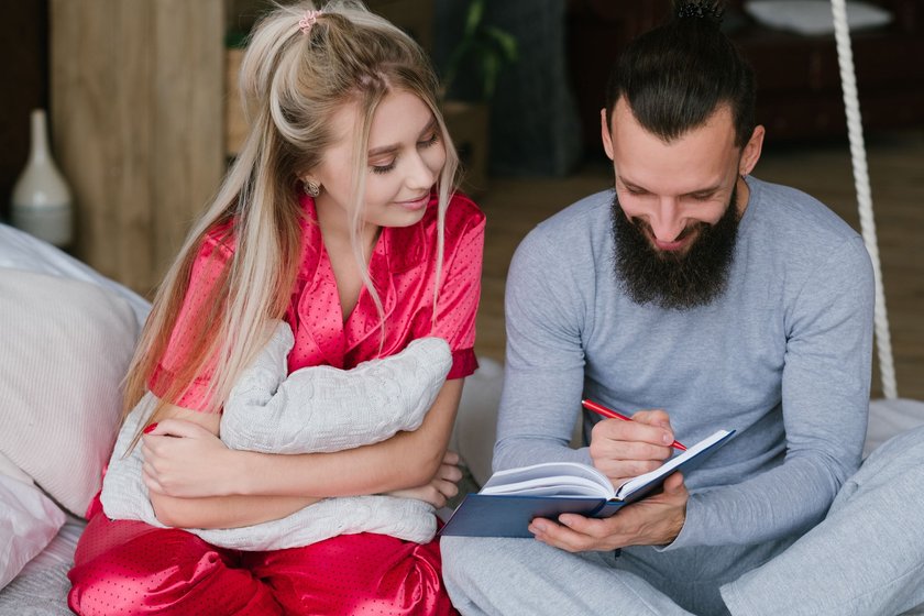 Paar sitzt auf Couch und macht Notizen