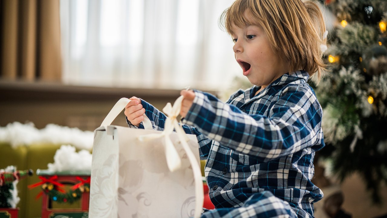 Geld sparen beim Weihnachtsgeschenke kaufen: Kind freut sich über Geschenk