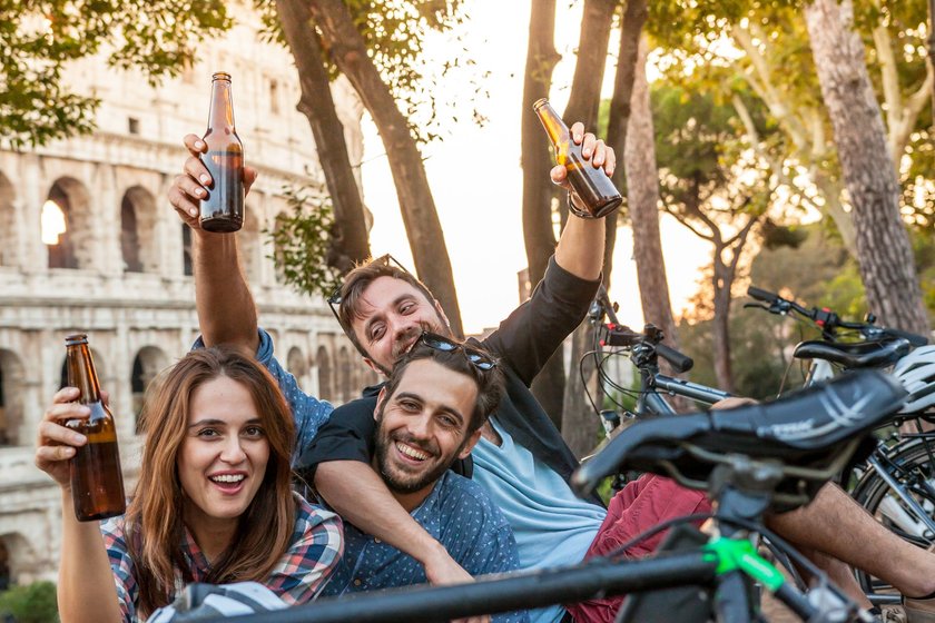 Drei Freunde trinken Bier vor dem Kolosseum in Rom