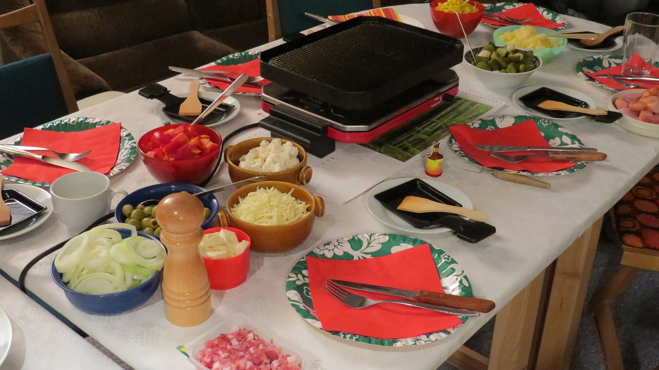 Raclette gemeinsam zubereiten am gedeckten Tisch macht Spaß.